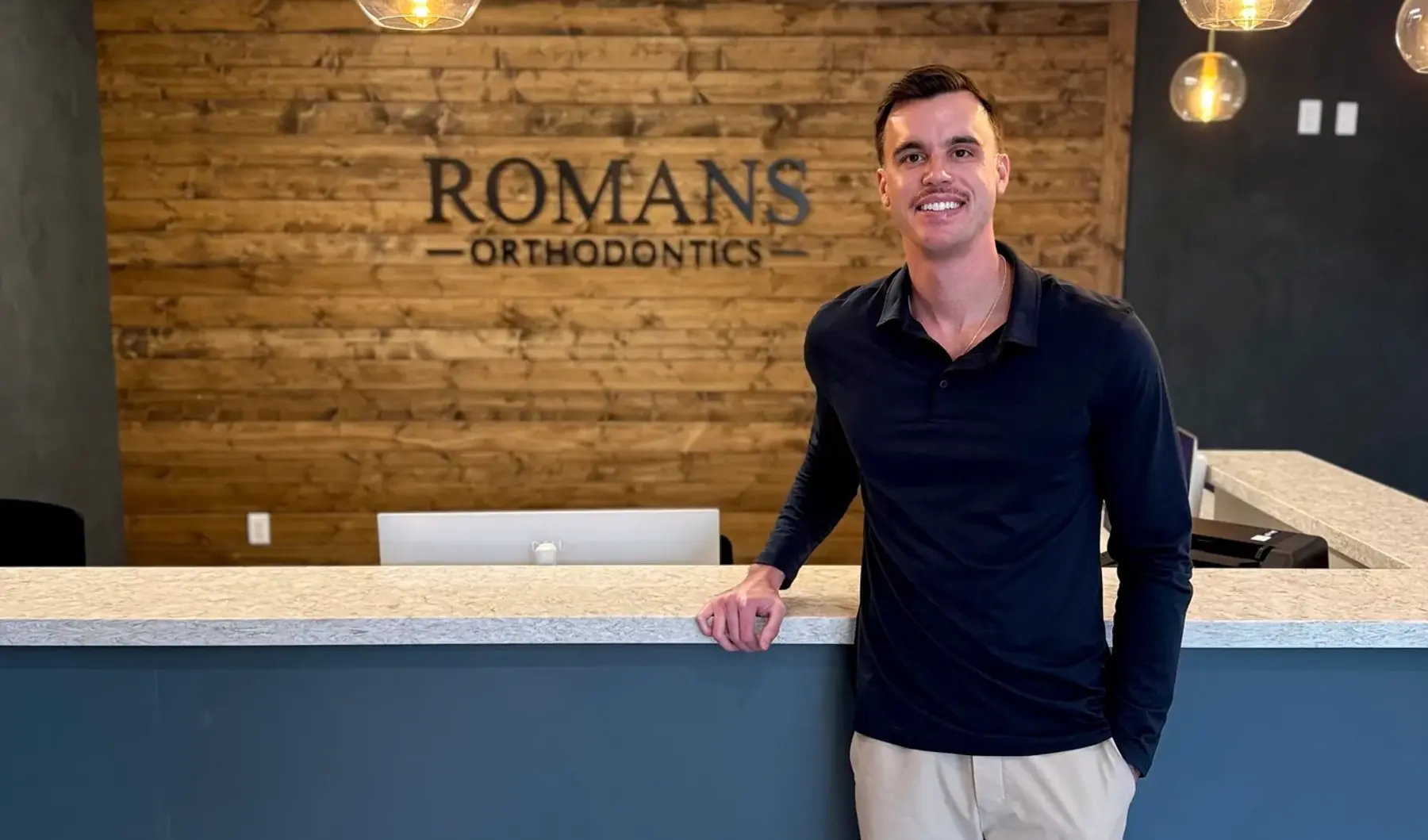 Dr. Nicholas Romans at the reception desk of Romans Orthodontics in Anthem, Arizona